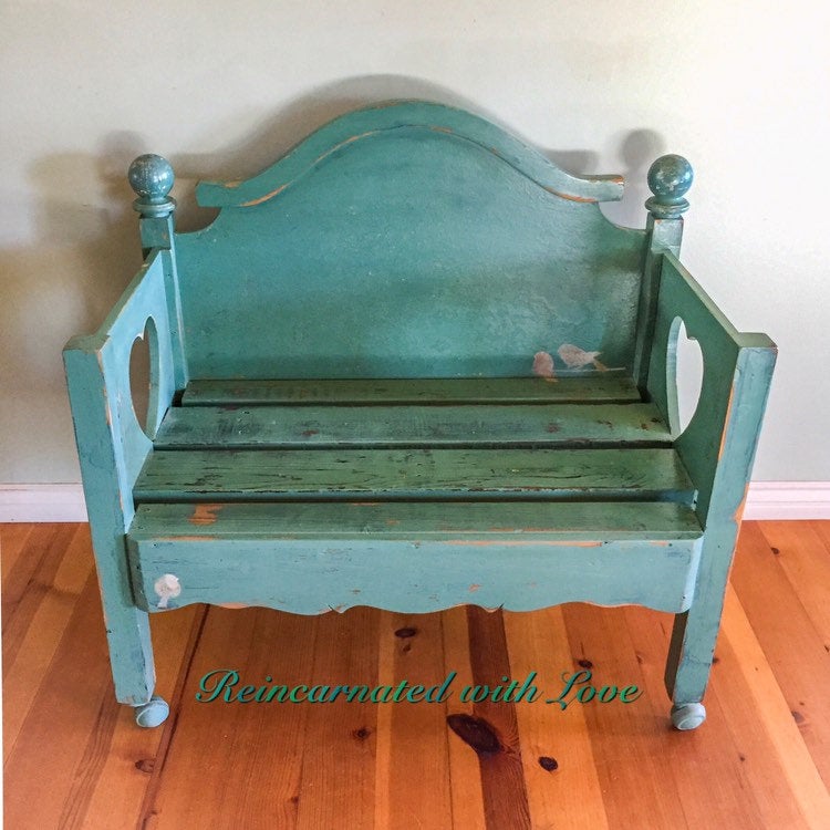 A shabby chic style bench, painted in distressed blue & green hues, with small bird accents.
