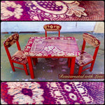 A kid’s table & three chairs, with a red base & distressed, red lace on the stained wood, tabletop & chair seats.
