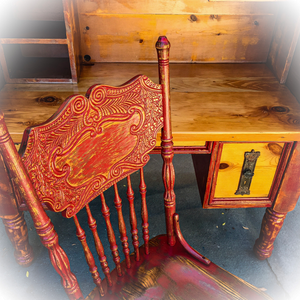 A farmhouse style, vintage desk, made of reclaimed wood, painted in distressed red on stained pine, with a matching chair.