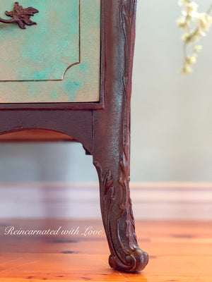 Close up of the wood carved detailing on a boho style dresser, done in a green, patina & rusted, iron finish.