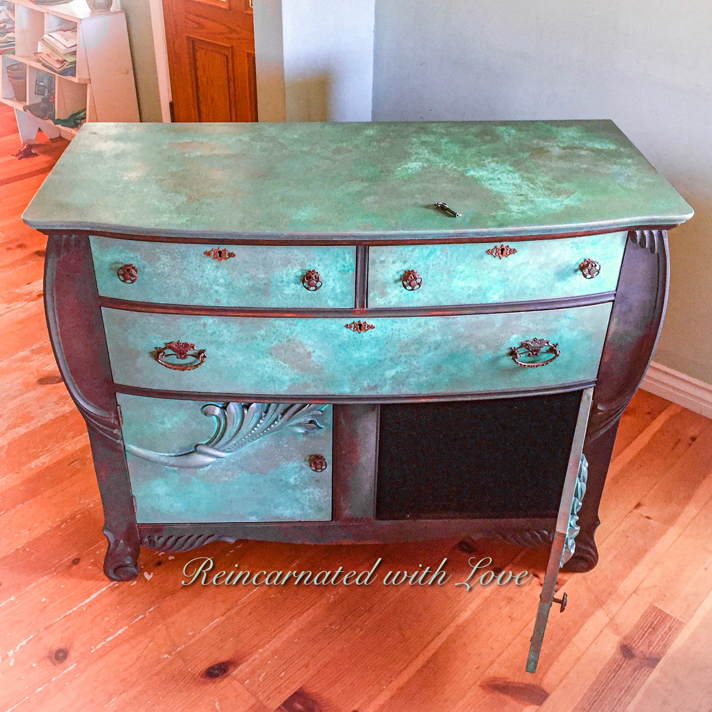 An antique dresser with art nouveau style, wood carved accents & a boho finish, done in rusted iron & green, copper patina.