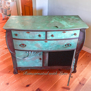 An antique dresser with art nouveau style, wood carved accents & a boho finish, done in rusted iron & green, copper patina.