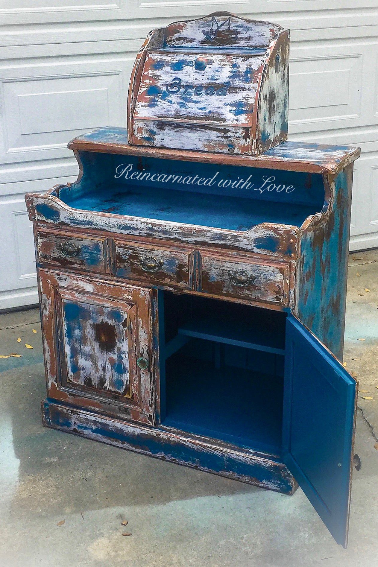 A farmhouse style, coffee bar, painted in a distressed blue, with it’s cabinet door open to display a large, storage area.