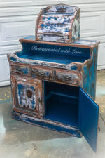 A farmhouse style, coffee bar, painted in a distressed blue, with it’s cabinet door open to display a large, storage area.