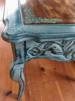A close up of the side table’s shabby chic finish, painted in distressed white with blue undertones.