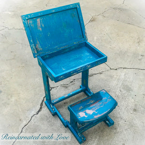 A shabby chic, child’s desk with an opening desktop & attached bench seat, painted & distressed in blue, with bird accents.