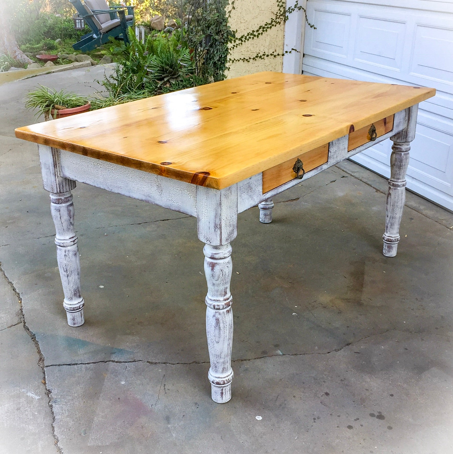 A country kitchen style table, with a knotted pine tabletop, two drawers & a distressed white base.