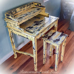Side view of a secretary style desk, painted in a rustic, yellow finish, with damask accents & a matching stool.