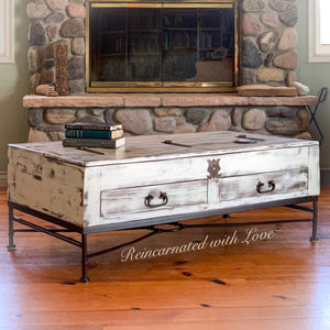 A lift top, coffee table, done in a distressed, white finish with wrought iron base & drawer pulls.