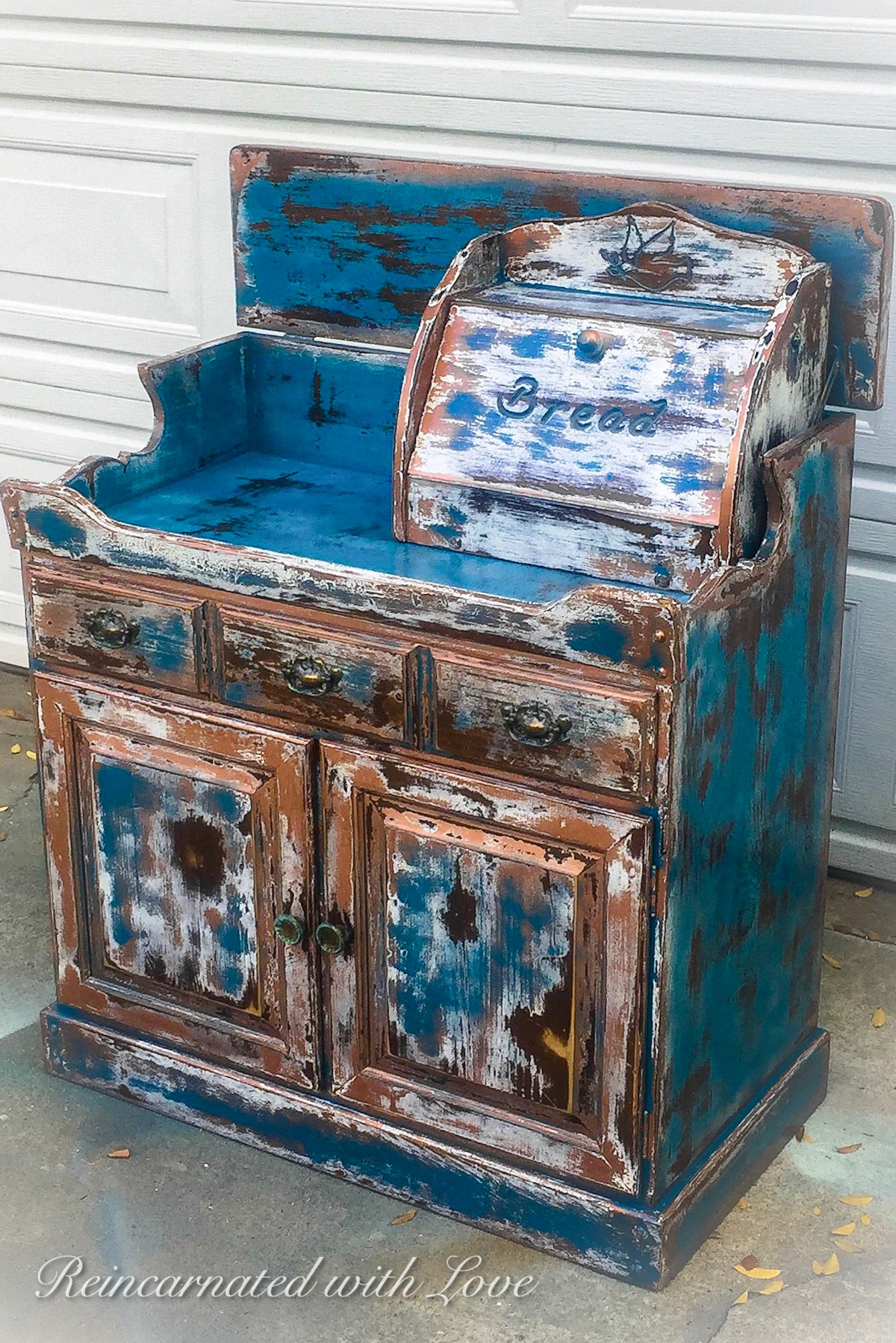 A piece of vintage furniture, repurposed into a farmhouse style, coffee bar, painted with a heavily distressed blue finish.