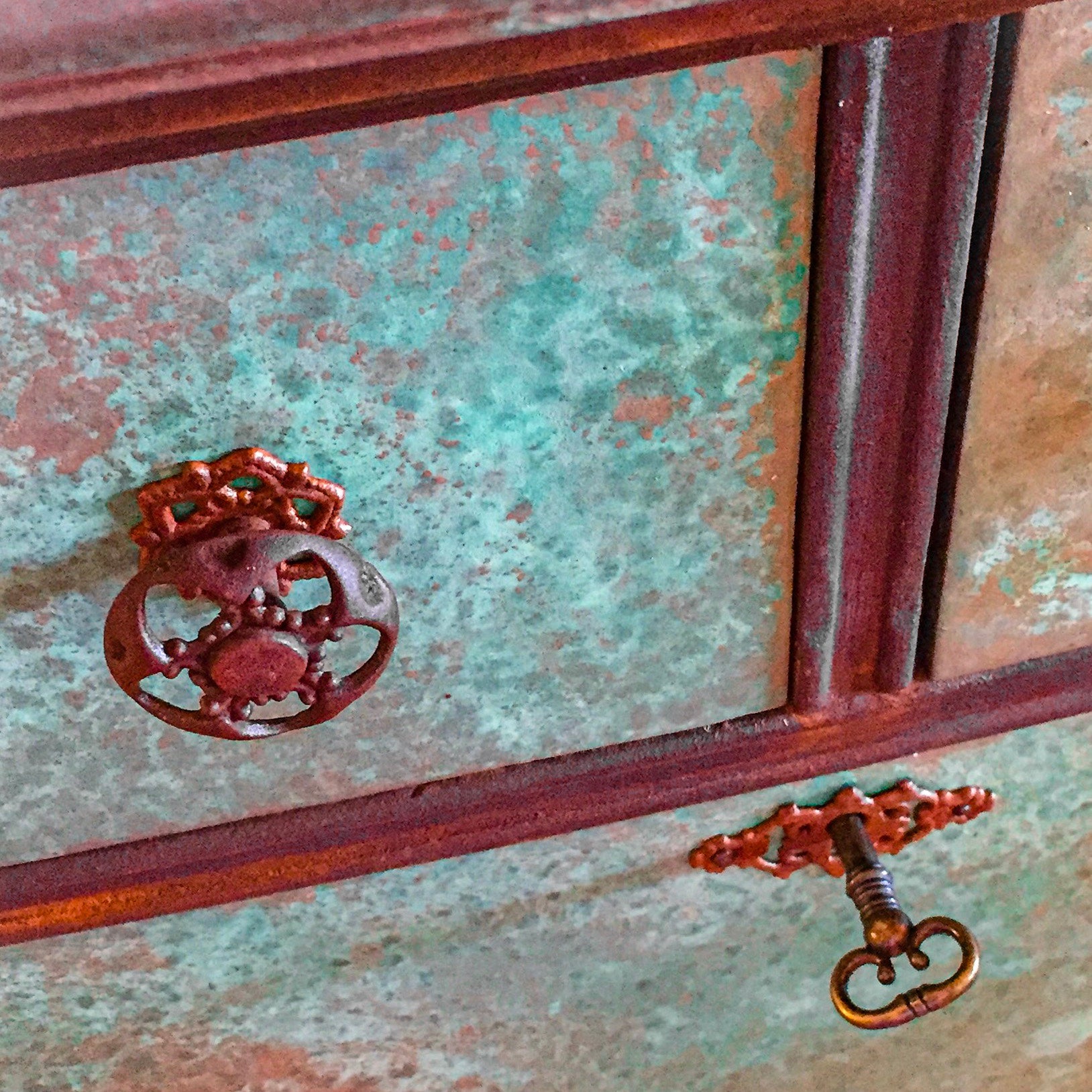 A close up of the drawer pull on an antique dresser with a working skeleton key, done in a boho style, patina finish.