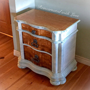 Farmhouse nightstand with three large drawers. Painted in shabby chic, white, with stained wood tabletop & drawer faces.