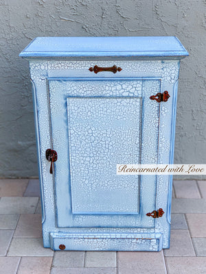 A shabby chic hamper, with a lift top lid, painted in distressed white with blue undertones on wood.