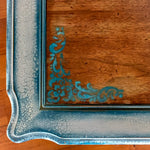 A close up of the damask accents on an end table with a stained wood tabletop & shabby chic style, white trim.