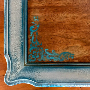 A close up of the damask accents on an end table with a stained wood tabletop & shabby chic style, white trim.