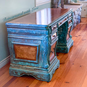 A side view of a boho style desk with a blue & green, patina finish over stained, burl wood inlay.