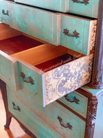 Close up of lace details on the drawer side panel of a boho style dresser, done in a green, patina & rusted, iron finish.