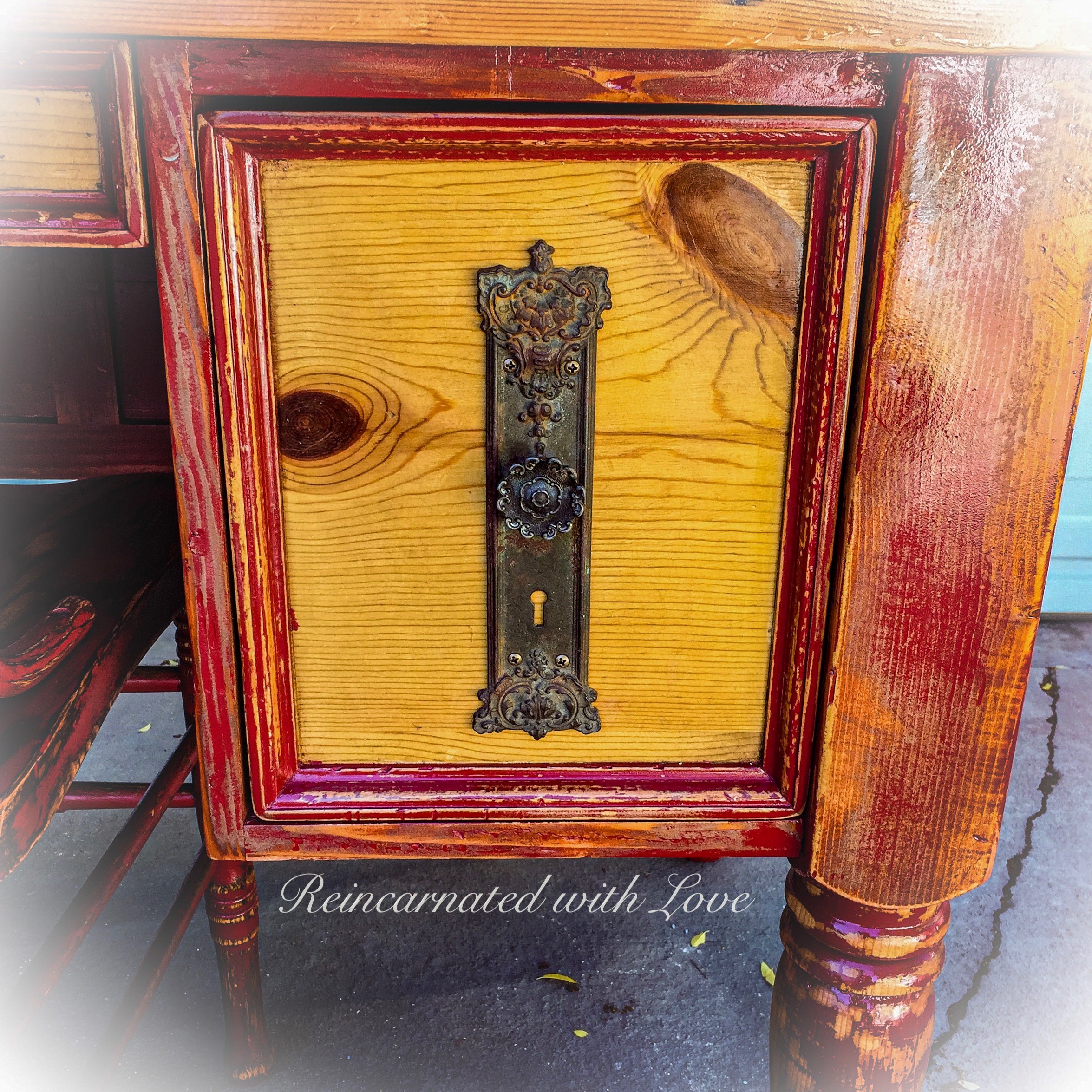 Antique hardware on the drawer face of a reclaimed wood desk, painted in distressed red & stained wood. 