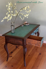 A French country, writing desk done in a rusted iron & green, patina finish with lace accents on the drawer’s side panels.