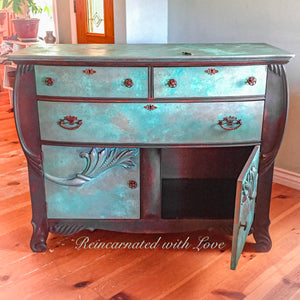 An antique dresser done in a rusted iron & green, patina finish with three drawers & a large cabinet area on the bottom.