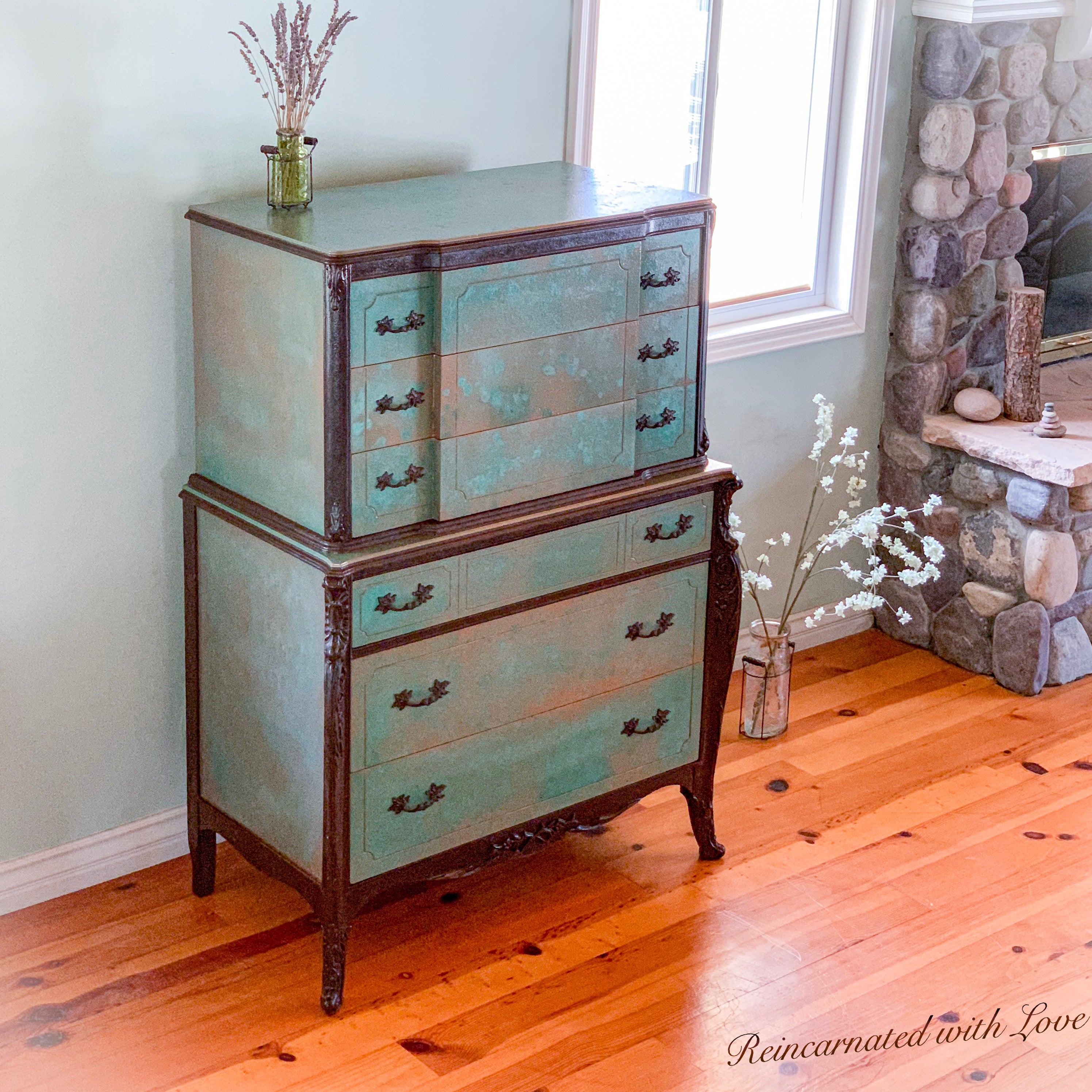 A tall, art-nouveau style, antique dresser, done in a green, patina finish with rusted iron accents.