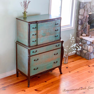 A tall, art-nouveau style, antique dresser, done in a green, patina finish with rusted iron accents.