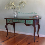 A French country, writing desk with three drawers. The boho style finish is a rusted iron & copper patina, with green hues.