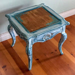 A shabby chic style, end table with a stained wood tabletop, distressed, white trim & blue hues.