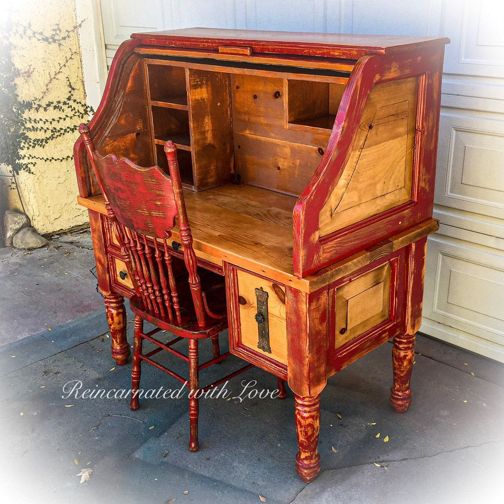 A farmhouse style, roll top desk & matching chair, painted with distressed red trim over stained wood.