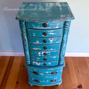 A French country style vintage jewelry armoire painted in distressed blue with white undertones.