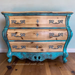 A bombe style chest of drawers done in a patina rusted, blue & green finish over stained wood.