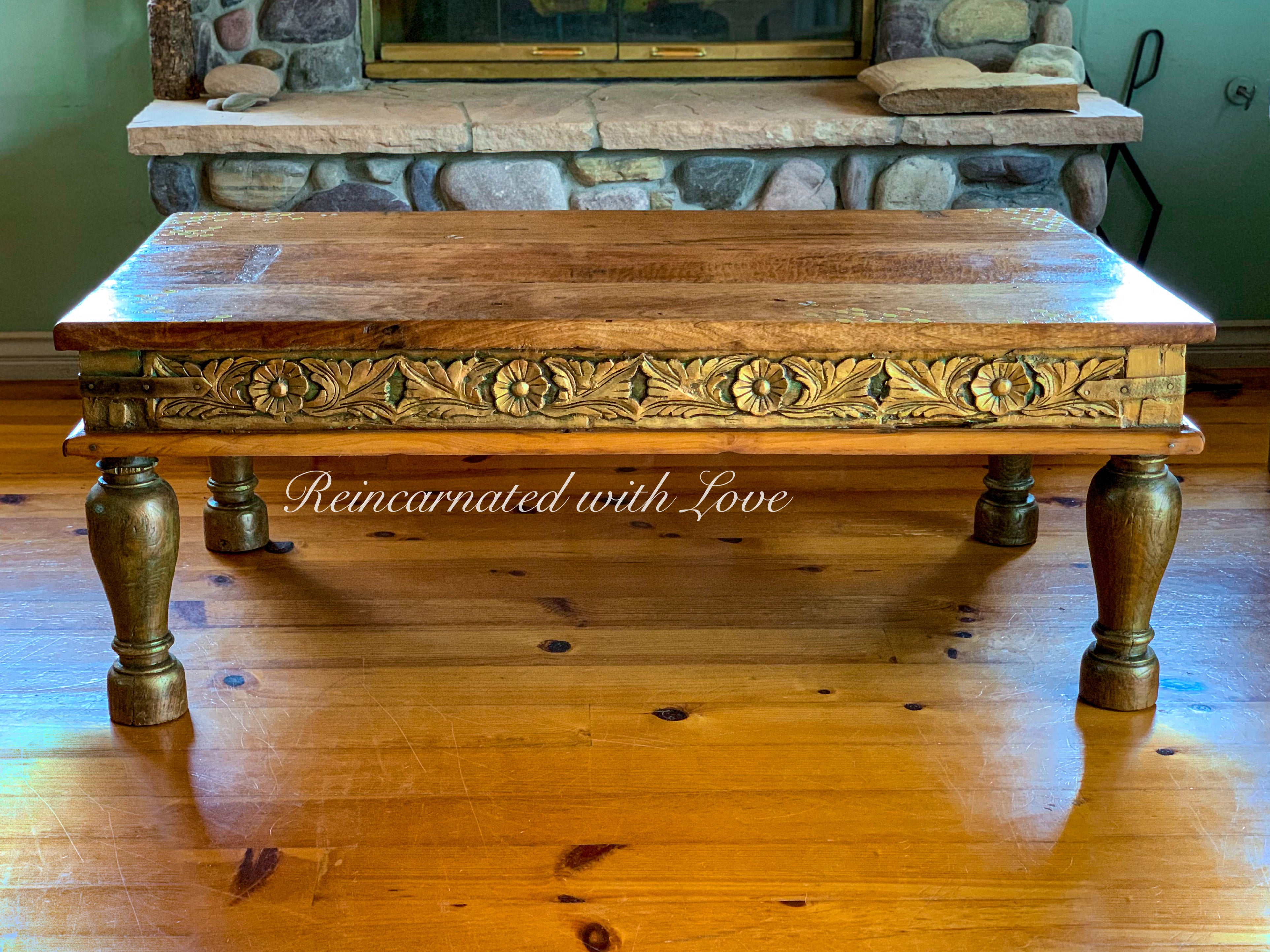 A reclaimed wood coffee table painted in distressed green with golden highlights over stained wood.