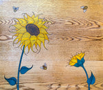 Top view of a vintage nightstand with sunflowers & bees burnt into the stained wood tabletop.