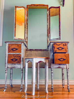 A French farmhouse style vanity table with an attached mirror and matching stool. Done in distressed white.