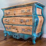 A bombe style chest of drawers done in a patina rusted, blue & green finish over stained wood.