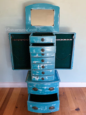 A vintage jewelry armoire painted in distressed blue with a hidden mirror & opening side panels.