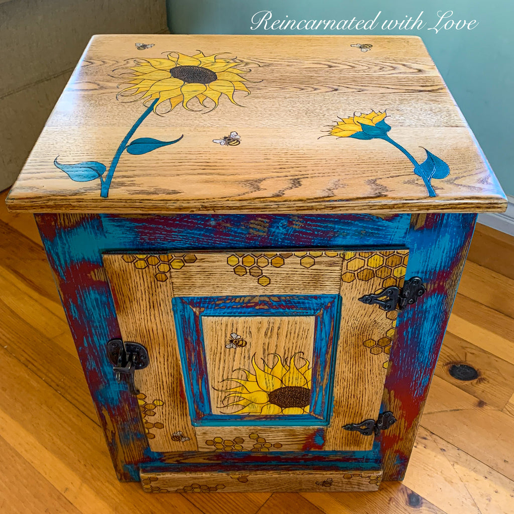 A nightstand done in distressed reds & blues on stained wood with sunflower, honeycomb & bee accents