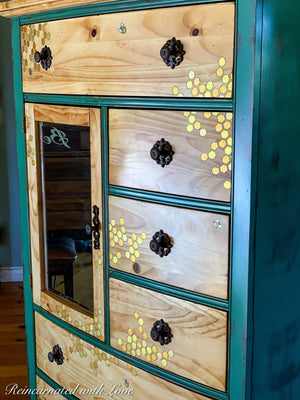 A vintage dresser painted in distressed green over stained wood with iridescent honeycomb accents.